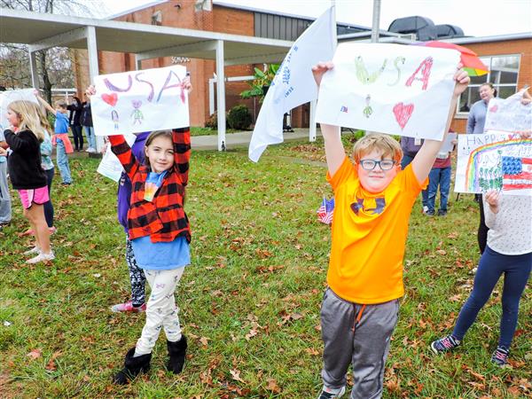 Students holding up homemade signs for a Veterans Day celebration.